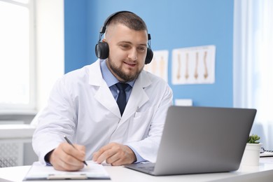 Photo of Doctor in headset having online consultation via laptop indoors