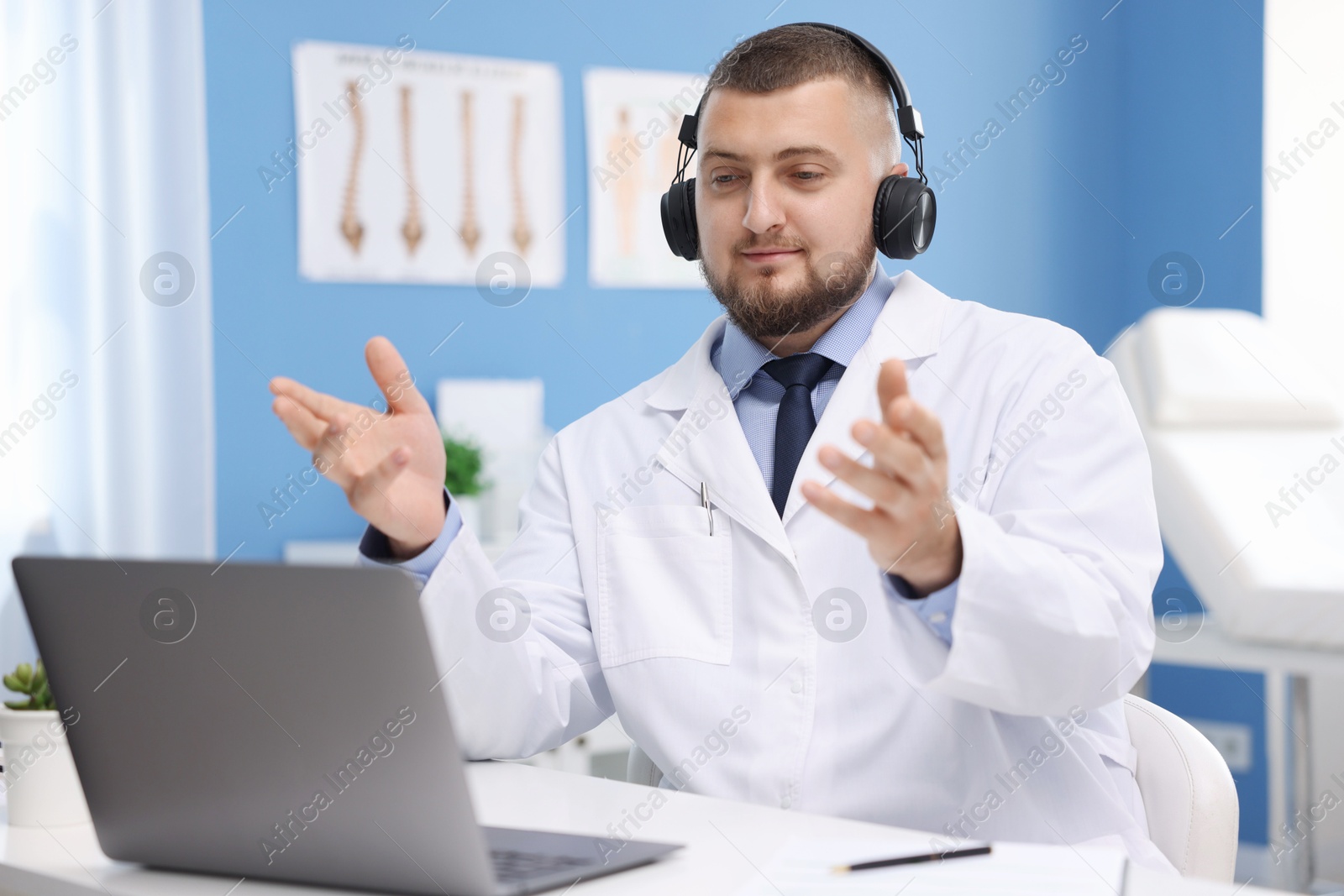 Doctor in headset having online consultation via laptop indoors Photo of Doctor in headset having online consultation via laptop indoors