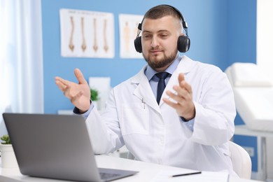 Photo of Doctor in headset having online consultation via laptop indoors