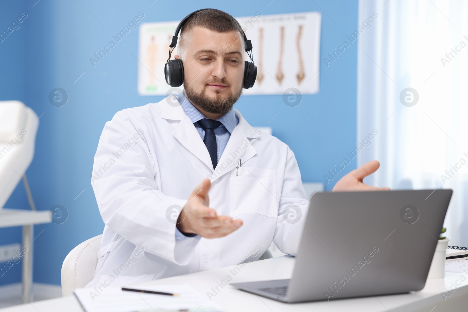 Doctor in headset having online consultation via laptop indoors Photo of Doctor in headset having online consultation via laptop indoors