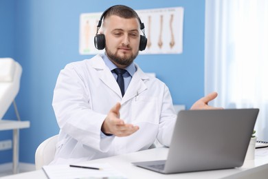 Photo of Doctor in headset having online consultation via laptop indoors