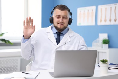 Photo of Doctor in headset having online consultation via laptop indoors