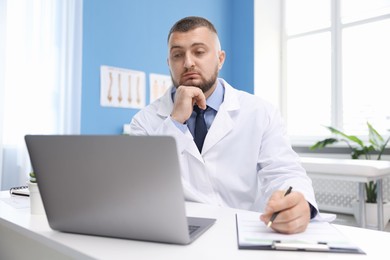 Photo of Doctor having online consultation via laptop in clinic