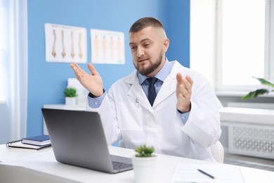 Photo of Doctor having online consultation via laptop in clinic