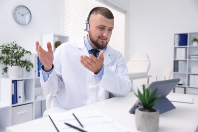 Photo of Doctor in headphones having online consultation via tablet indoors