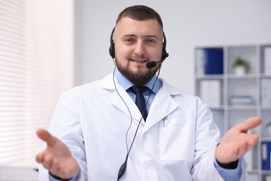 Photo of Doctor with headset having online consultation in clinic