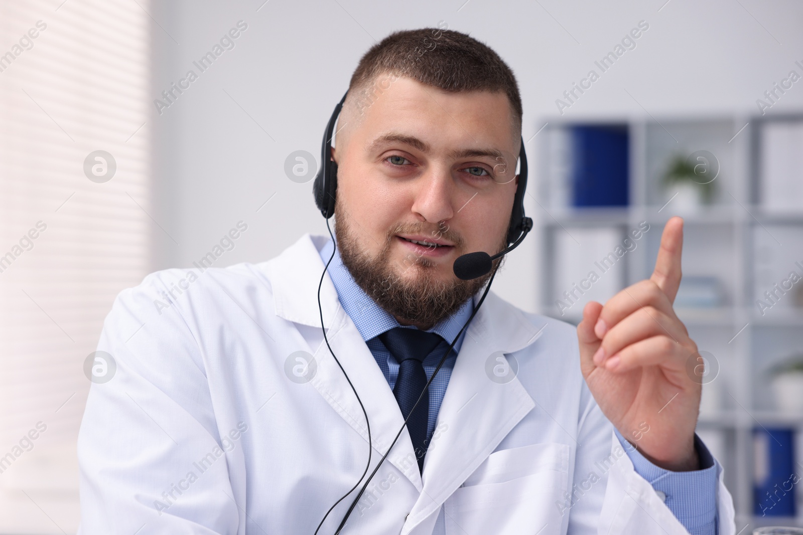 Doctor with headset having online consultation in clinic Photo of Doctor with headset having online consultation in clinic