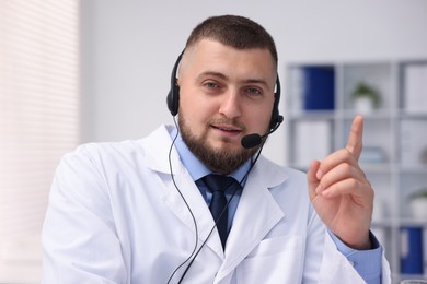 Photo of Doctor with headset having online consultation in clinic