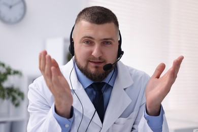 Photo of Doctor with headset having online consultation in clinic