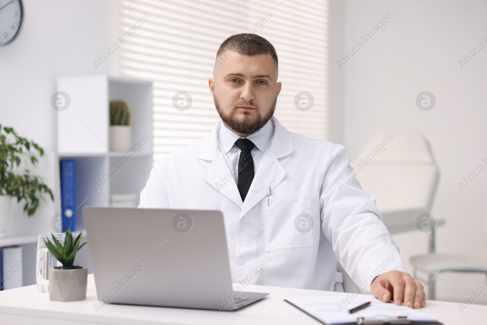 Doctor working at table with laptop in clinic. Online medical consultation Photo of Doctor working at table with laptop in clinic. Online medical consultation