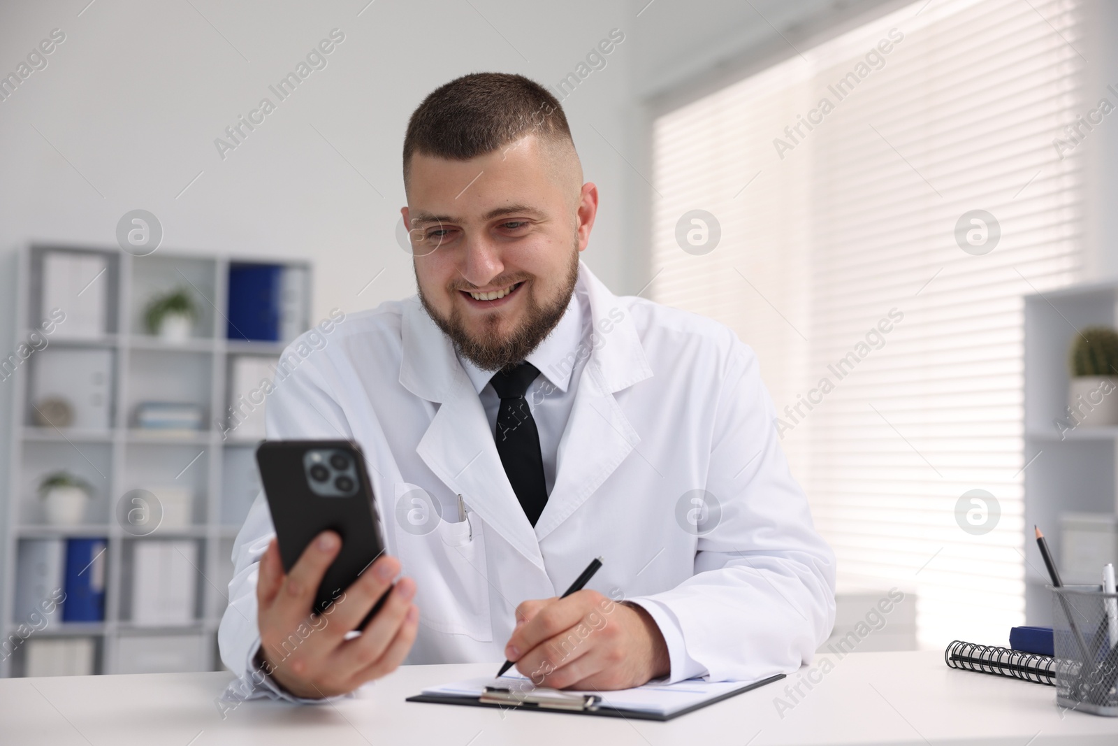 Doctor having online consultation via smartphone in clinic Photo of Doctor having online consultation via smartphone in clinic
