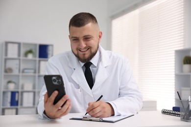 Photo of Doctor having online consultation via smartphone in clinic