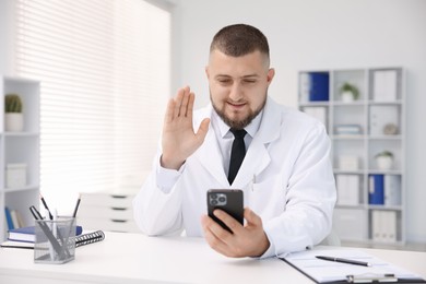 Photo of Doctor having online consultation via smartphone in clinic