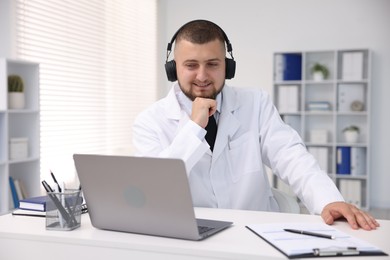 Photo of Doctor in headphones having online consultation via laptop indoors