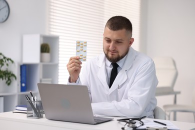 Photo of Doctor with pills having online consultation via laptop in clinic