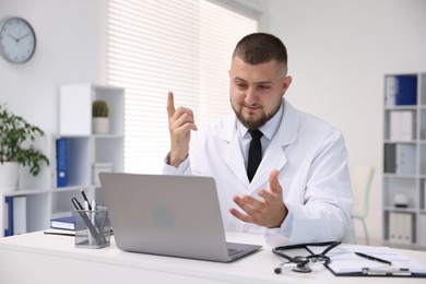 Photo of Doctor having online consultation via laptop in clinic