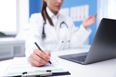 Photo of Doctor having online consultation via laptop in clinic, selective focus