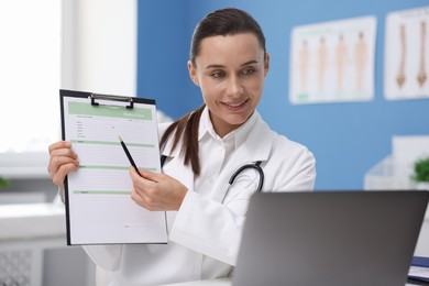 Photo of Doctor having online consultation via laptop in clinic