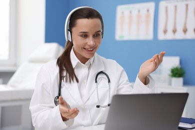 Photo of Doctor in headphones having online consultation via laptop indoors