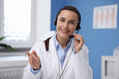 Photo of Doctor with headset having online consultation in clinic