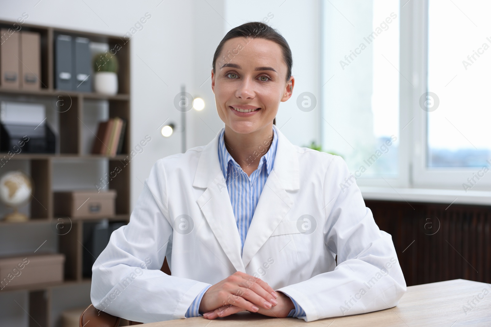 Photo of Portrait of happy doctor in uniform at table indoors