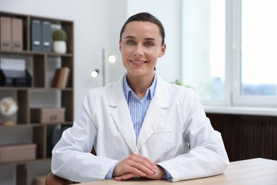Photo of Portrait of happy doctor in uniform at table indoors