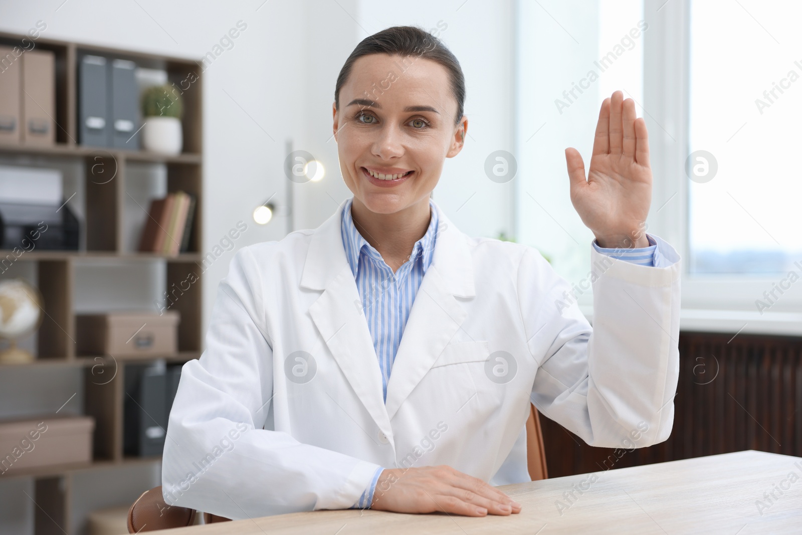 Photo of Portrait of happy doctor in uniform at table indoors