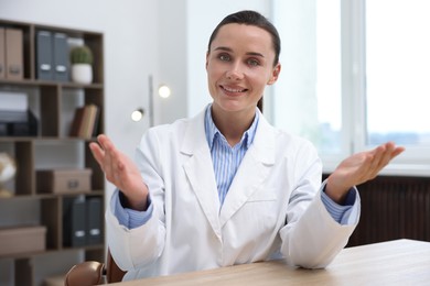 Photo of Portrait of happy doctor in uniform at table indoors