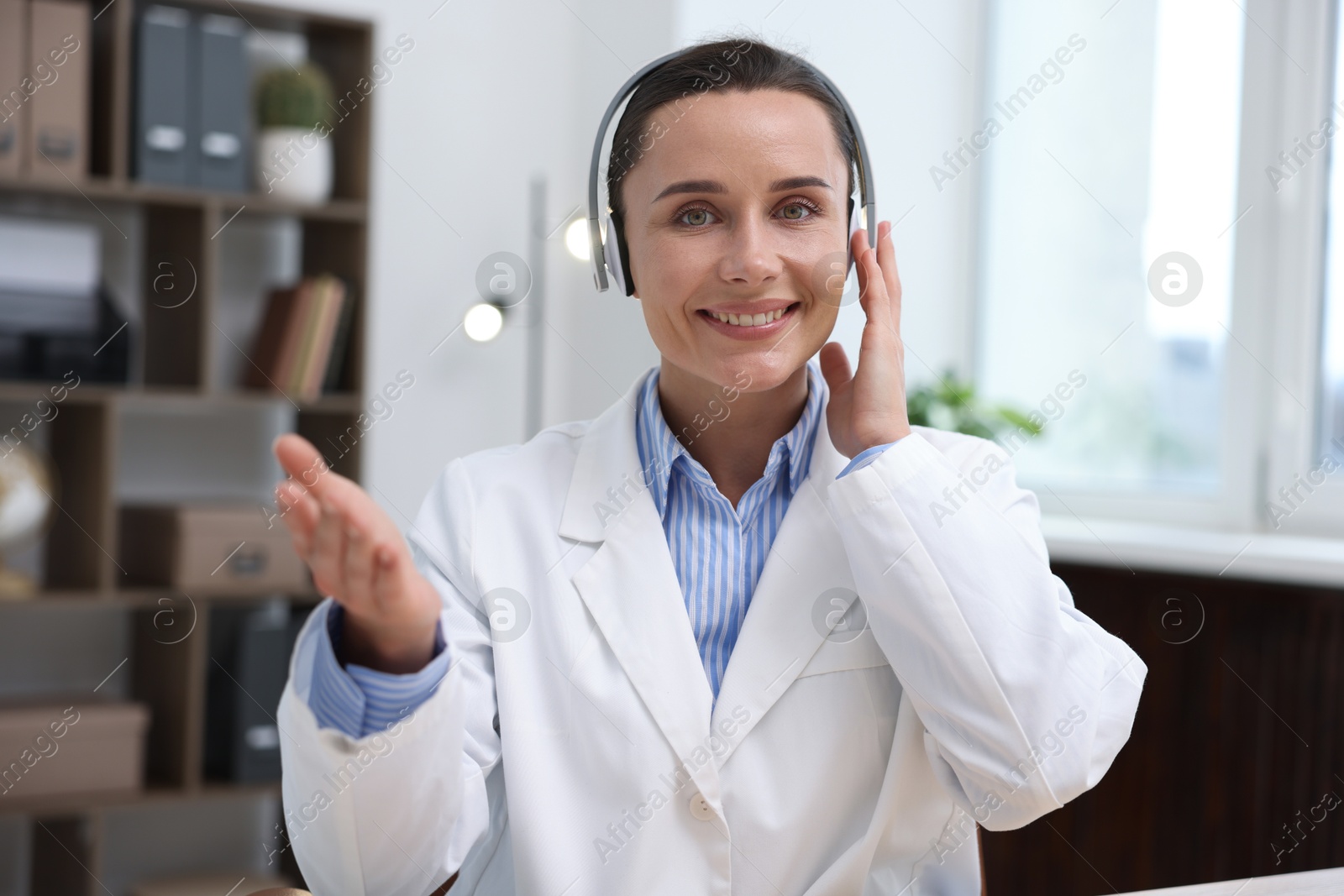 Doctor with headphones having online consultation in clinic Photo of Doctor with headphones having online consultation in clinic