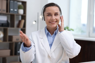 Photo of Doctor with headphones having online consultation in clinic