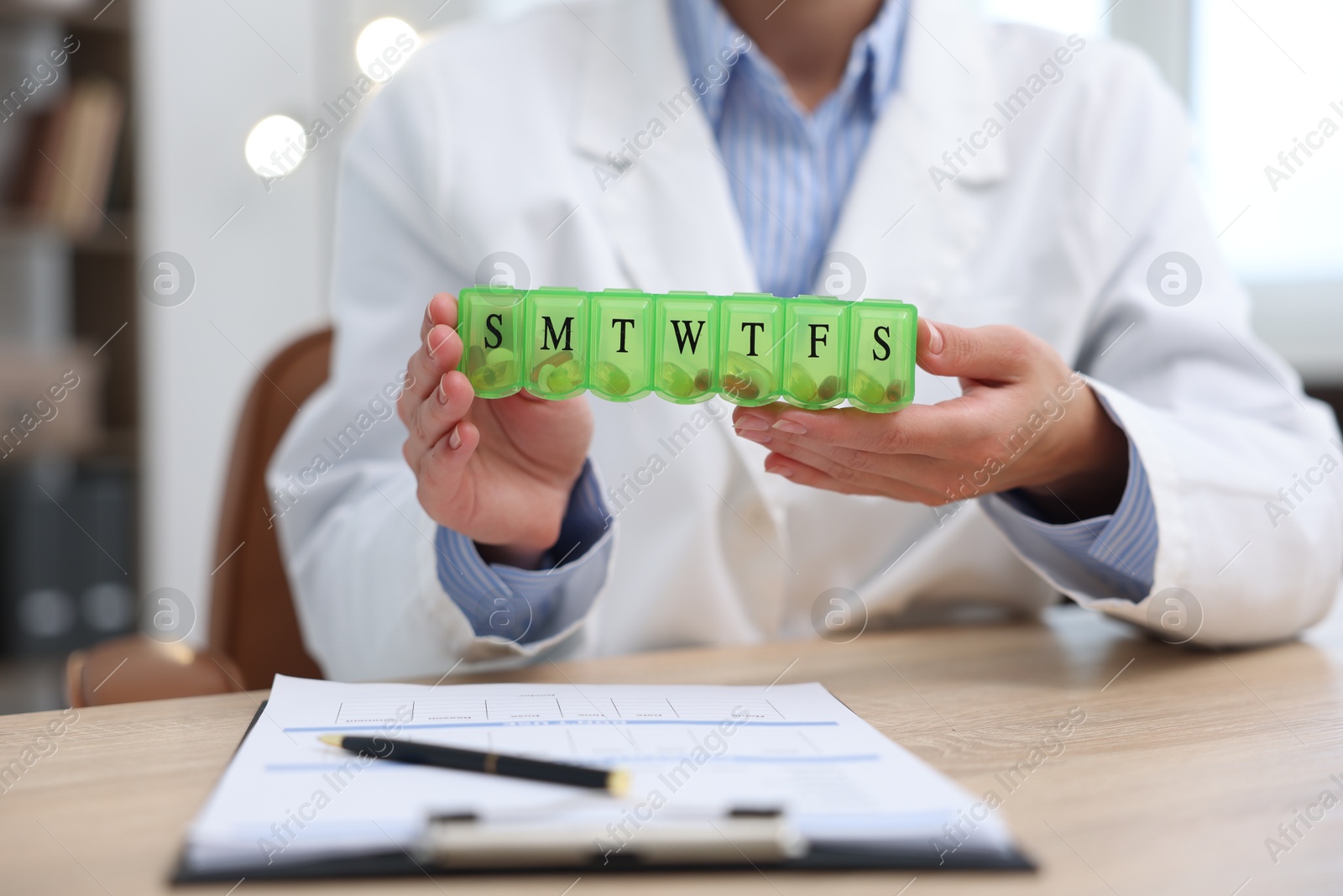 Photo of Doctor with pill box at table in clinic, closeup