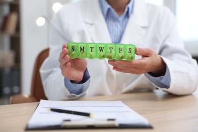 Photo of Doctor with pill box at table in clinic, closeup