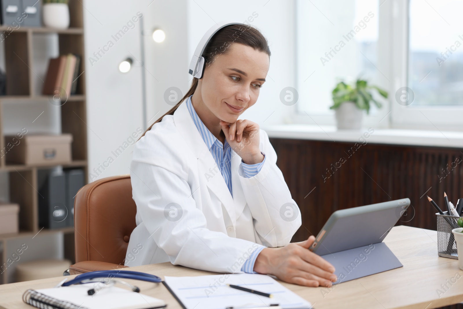 Doctor in headphones having online consultation via tablet indoors Photo of Doctor in headphones having online consultation via tablet indoors