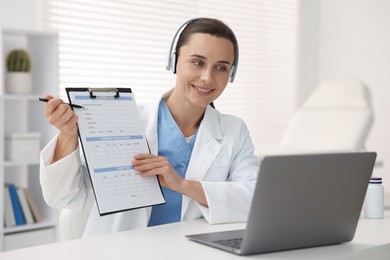 Photo of Doctor in headphones having online consultation via laptop indoors