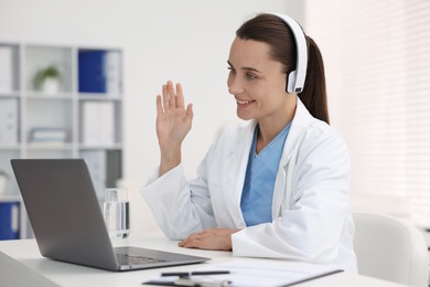 Photo of Doctor in headphones having online consultation via laptop indoors