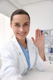 Photo of Doctor having online consultation at table in clinic