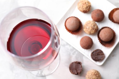 Photo of Red wine in glass and truffle bonbons on light table, above view