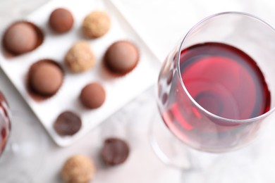 Photo of Red wine in glass and truffle bonbons on light table, above view