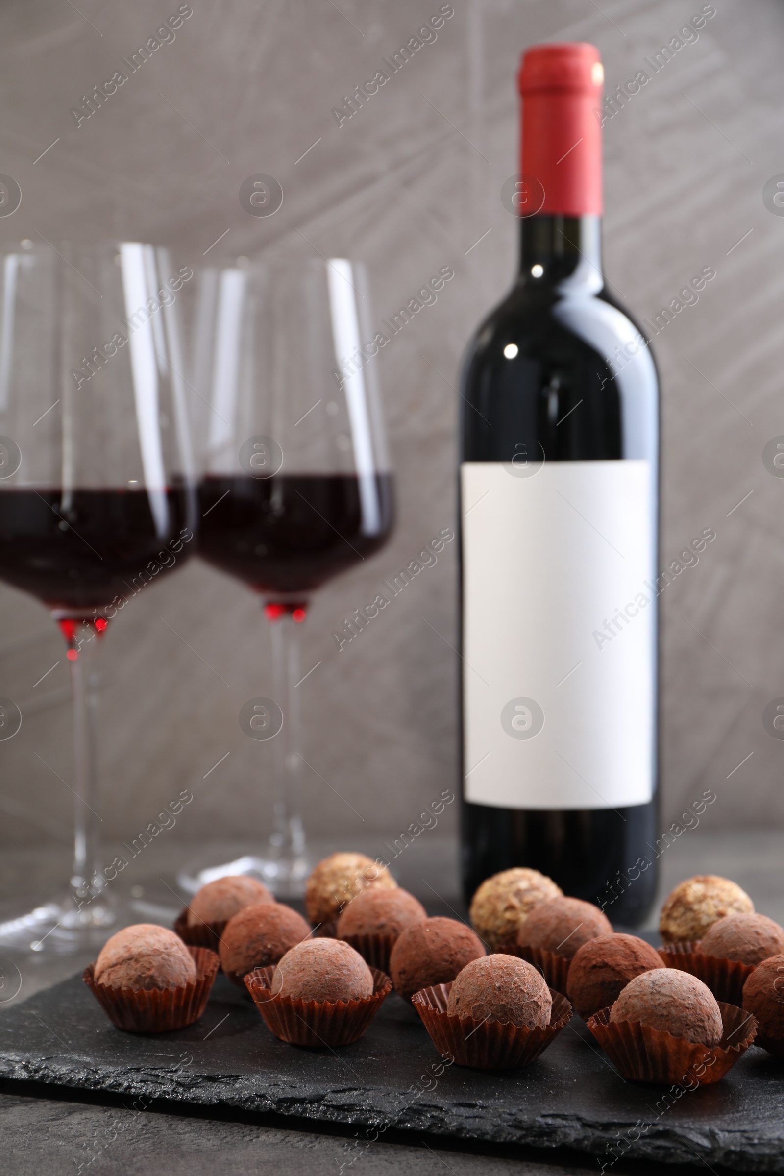 Tasty truffle bonbons and red wine on grey textured table, closeup Photo of Tasty truffle bonbons and red wine on grey textured table, closeup