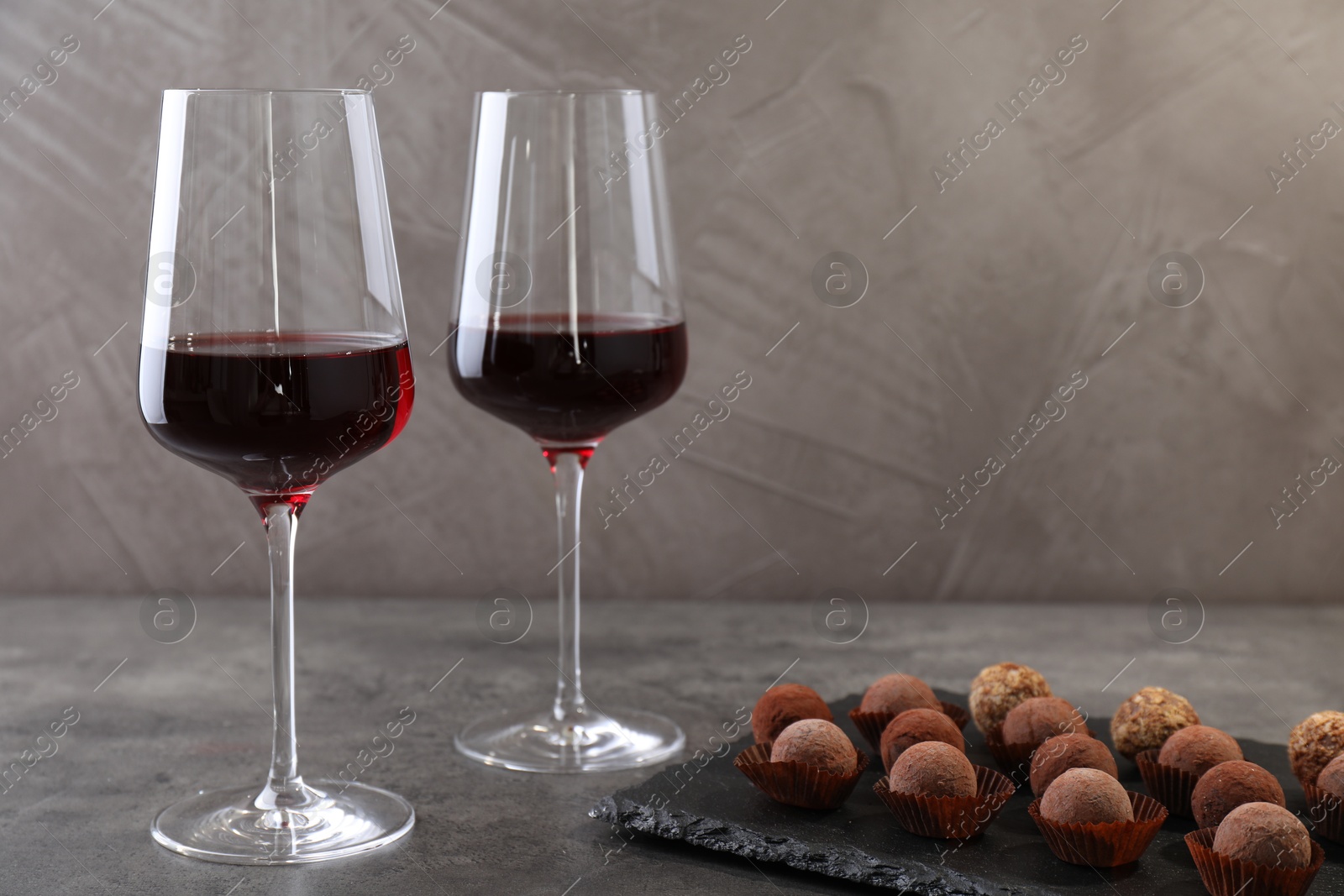 Tasty truffle bonbons and red wine on grey textured table, closeup Photo of Tasty truffle bonbons and red wine on grey textured table, closeup