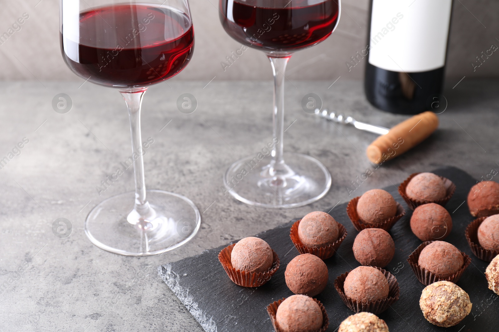 Tasty truffle bonbons and red wine on grey textured table, closeup Photo of Tasty truffle bonbons and red wine on grey textured table, closeup