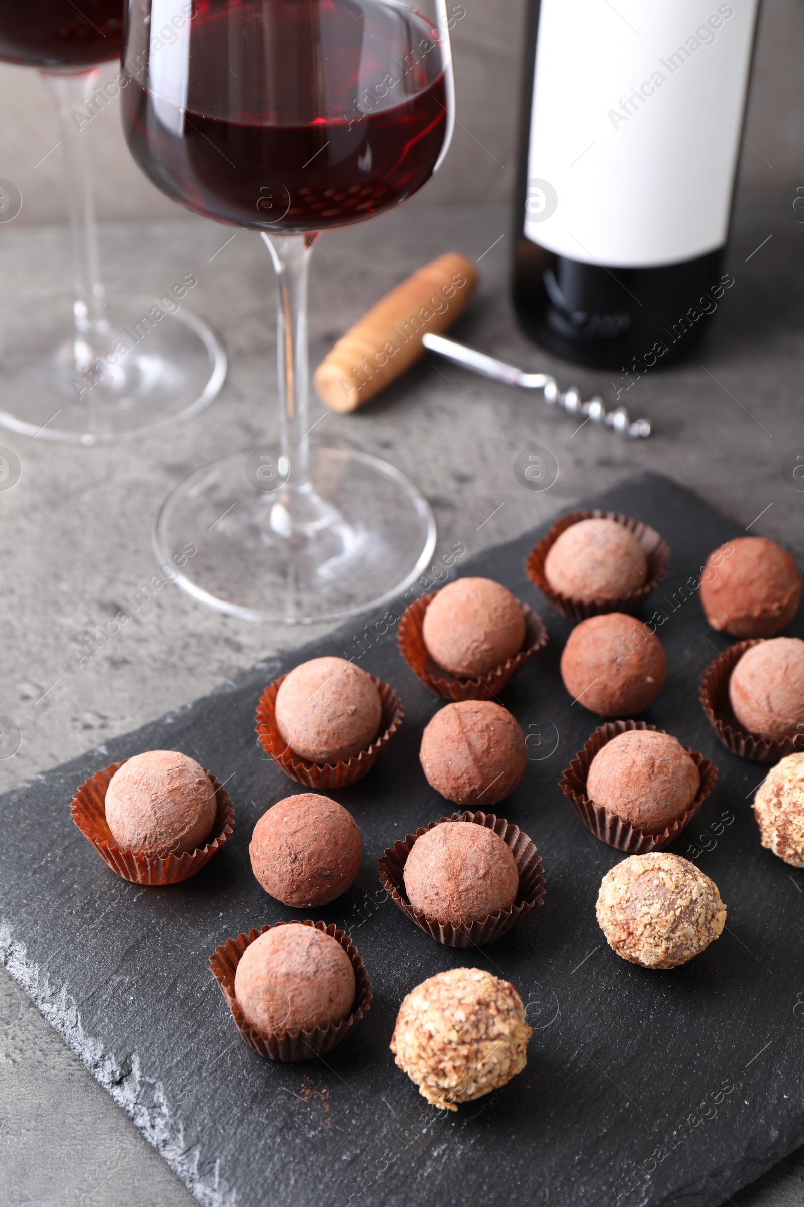 Tasty truffle bonbons and red wine on grey textured table, closeup Photo of Tasty truffle bonbons and red wine on grey textured table, closeup