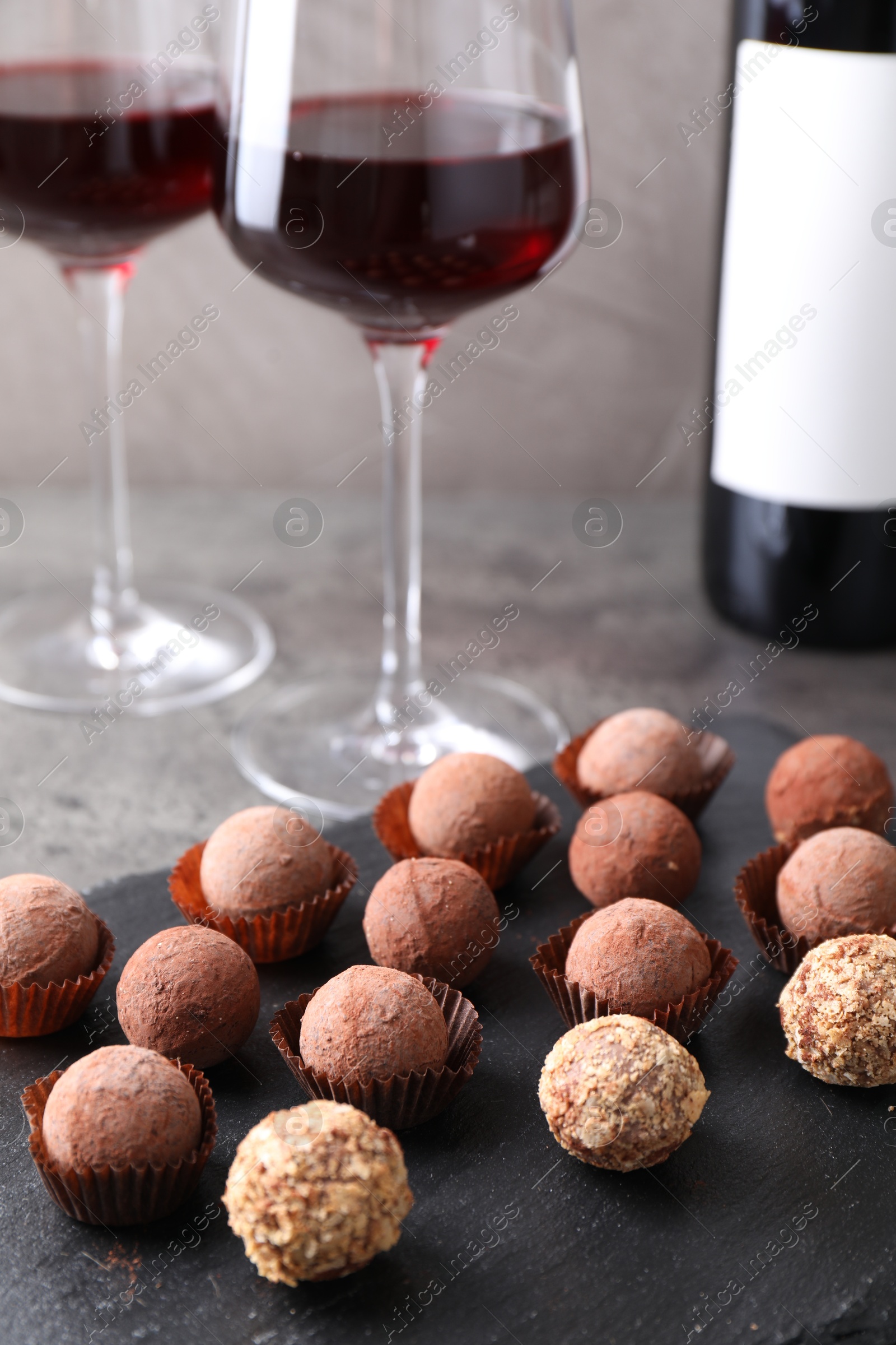 Tasty truffle bonbons and red wine on grey table, closeup Photo of Tasty truffle bonbons and red wine on grey table, closeup