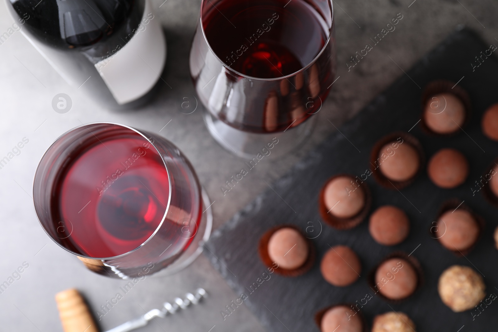 Red wine in glasses and tasty truffle bonbons on grey table, flat lay Photo of Red wine in glasses and tasty truffle bonbons on grey table, flat lay