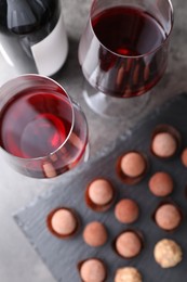 Photo of Tasty truffle bonbons and red wine on grey table, flat lay