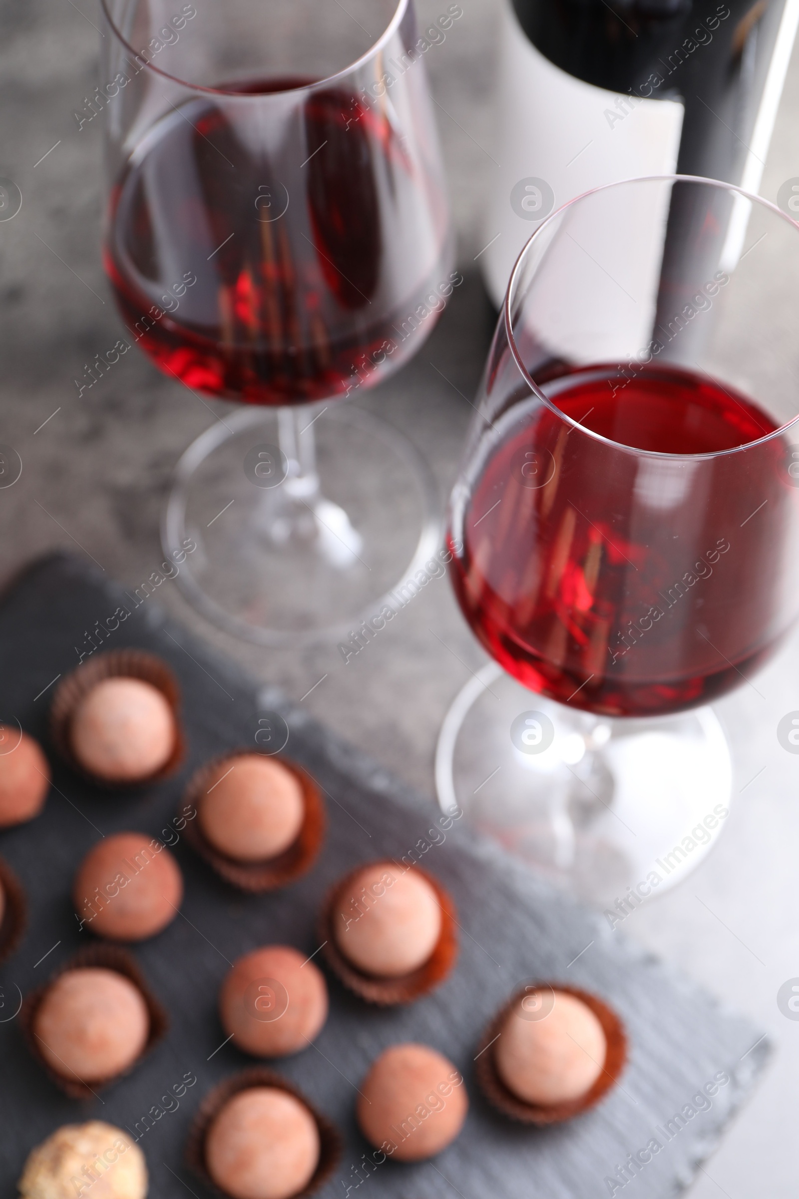 Tasty truffle bonbons and red wine on grey table, selective focus Photo of Tasty truffle bonbons and red wine on grey table, selective focus