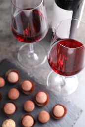 Photo of Tasty truffle bonbons and red wine on grey table, selective focus