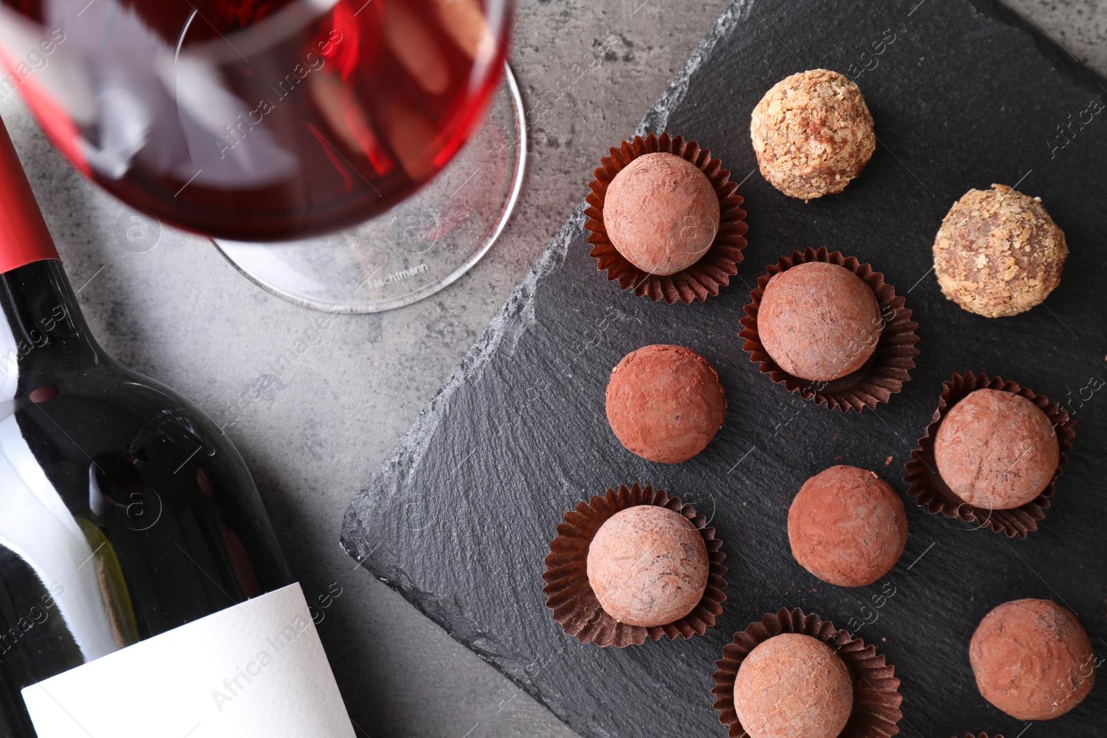 Tasty truffle bonbons and red wine on grey textured table, flat lay Photo of Tasty truffle bonbons and red wine on grey textured table, flat lay