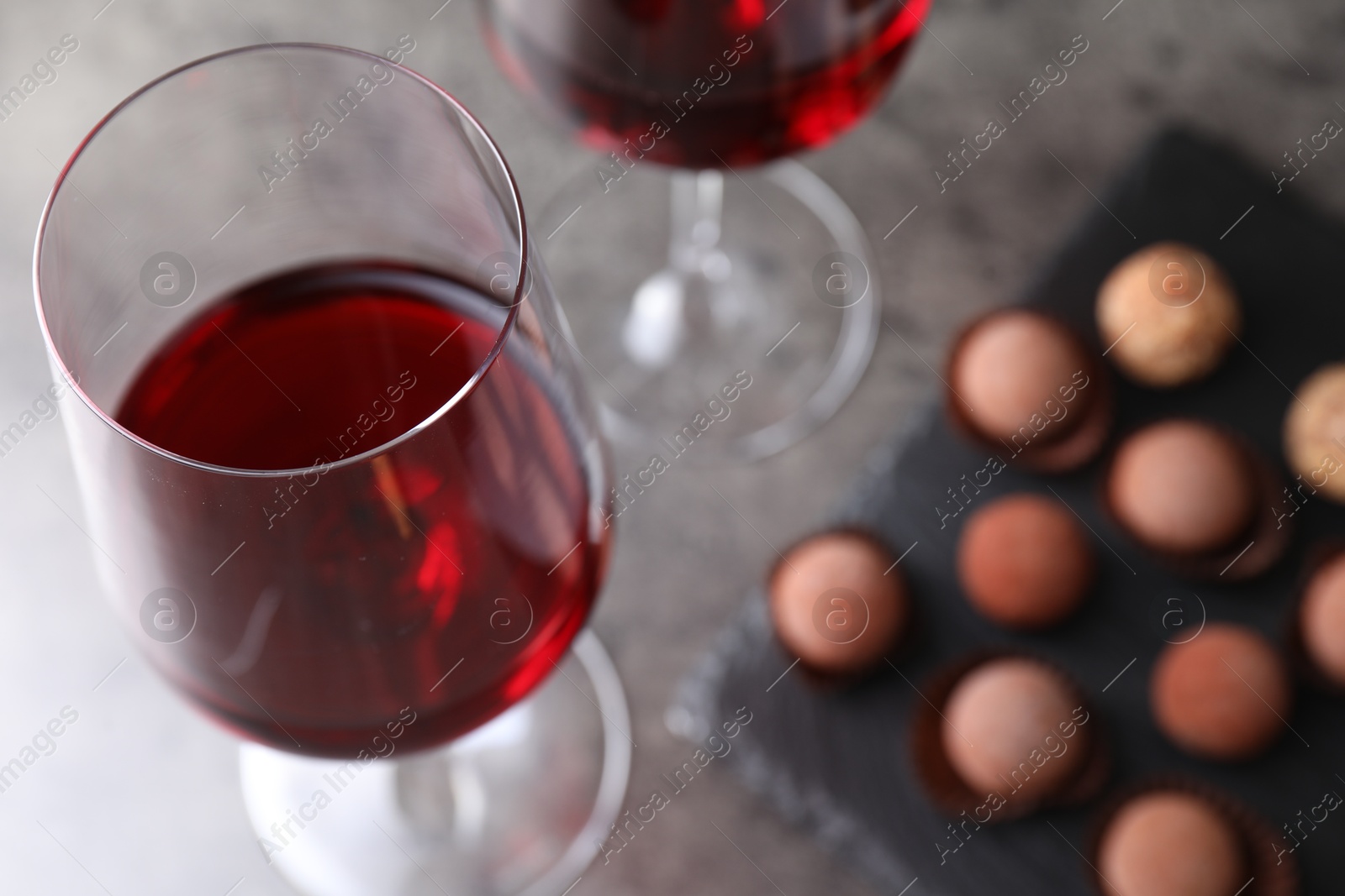 Red wine in glasses and tasty truffle bonbons on grey table, selective focus Photo of Red wine in glasses and tasty truffle bonbons on grey table, selective focus