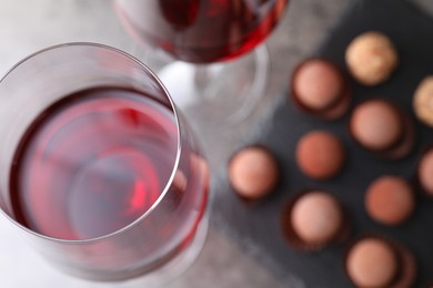 Photo of Red wine in glasses and tasty truffle bonbons on grey table, selective focus